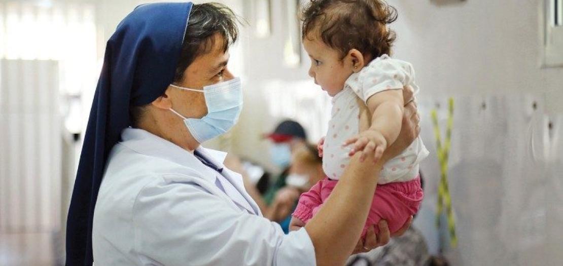 Good Shepherd Sister Antoinette Assaf assesses a child at St. Anthony Community Health Center in Roueissat